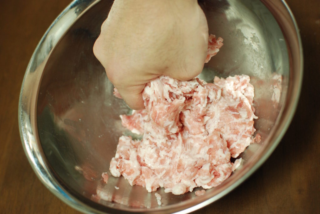 ３　豚肉をボウルに入れてもみ込むようにして混ぜ、調味料を入れてよく練り混ぜる